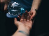 Close-up shot of water being poured from a plastic bottle into open hands, emphasizing cleanliness and refreshment.