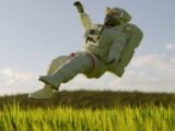 a person in a space suit in the air above grass