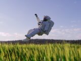a person in a white suit jumping in a field of grass