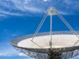 A large satellite dish with a clear blue sky in the background, showcasing modern communication technology.