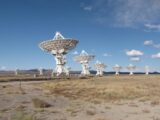 Explore the expansive array of radio telescopes in open terrain under a vibrant blue sky.