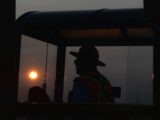 A man in a cowboy hat standing in front of a bus