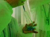 Close-up of a scientist using a syringe to handle chemicals in a laboratory setting.