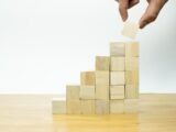 A person placing a piece of wood into a pyramid
