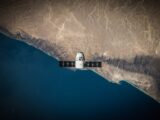 A satellite hovering above Earth's coastline, captured from space.
