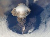 Stunning bird's eye view of a volcanic eruption with massive ash cloud and smoke plumes.
