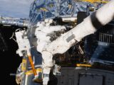 a man in a white space suit is outside of a space station