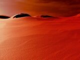 a group of hills covered in sand under a cloudy sky