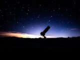 a telescope sitting on top of a hill under a night sky