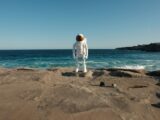 A man in a white suit standing on a beach